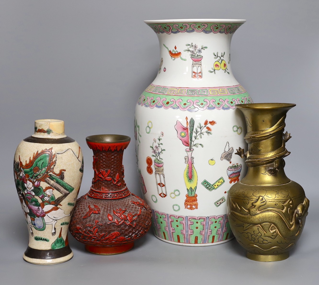 A Chinese crackle glaze ‘warriors’ vase, a famille rose ‘hundred antiques’ vase, a ‘cinnabar’ lacquer vase and a bronze ‘dragon’ vase, tallest 38cm